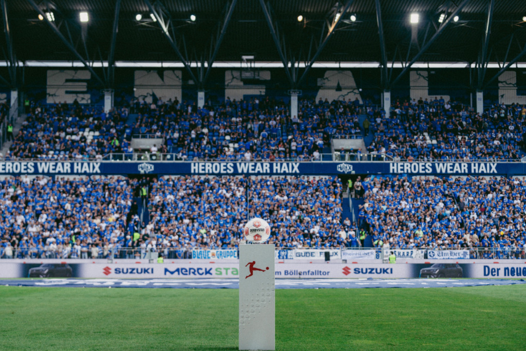 Der neue Spielbal der 2. Bundesliga mit Fans vom SV 98 im Hintergrund.